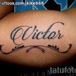 Фото татуировки с надписью 'Victor', выполненной черными и коричневыми чернилами на руке, украшенной декоративными узорами. Стильный и оригинальный рисунок татуировки.