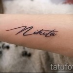 Фото минималистичной татуировки с именем 'Nikita', выполненной тонкой линией на руке. Небольшая, изящная татуировка.