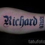 Фото тату с именем 'Richard', выполненное в готическом стиле, с добавлением даты '071121' на предплечье. Черно-серая татуировка с острыми углами.