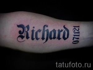 Фото тату с именем 'Richard', выполненное в готическом стиле, с добавлением даты '071121' на предплечье. Черно-серая татуировка с острыми углами.