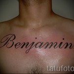 Фото тату с именем 'Benjamin', выполненное классическим шрифтом на груди мужчины. Черно-серая татуировка с четкими линиями.