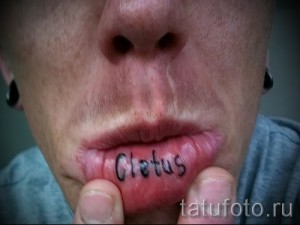Фото тату надписи 'Cletus' на нижней губе. Черные чернила, простой шрифт, провокационный и необычный дизайн. Подходит для тех, кто не боится экспериментировать.