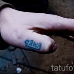 Фото тату надписи 'Sasha' на пальце руки. Синие чернила, простой шрифт, минималистичный дизайн. Подходит для тех, кто предпочитает небольшие и незаметные татуировки.