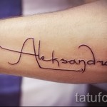 Фото тату надписи 'Aleksandra' на предплечье. Тонкие линии, каллиграфический шрифт, минималистичный дизайн. Идеально для любителей лаконичных татуировок.