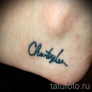 Фото тату надписи 'Christofer' на лодыжке. Черные чернила, тонкие линии, каллиграфический шрифт. Идеально для любителей минимализма и персонализированных татуировок.