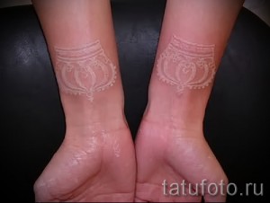 Фото пары белых татуировок на запястьях. Симметричные орнаменты с геометрическими формами и цветочными элементами. Эскиз тату для пар.