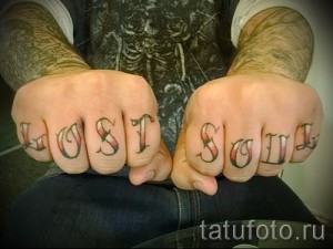 Фото тату с надписью 'LOST SOUL' на костяшках пальцев, выполненной в олдскульном стиле. Яркие цвета и четкие контуры.