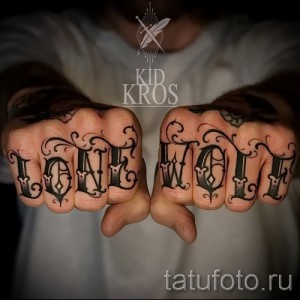 Фото татуировок с надписью 'Lone Wolf' на костяшках пальцев, выполненных черными чернилами в готическом стиле.