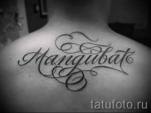 Фото тату с именем Mangubat, выполненное изящным шрифтом с декоративными элементами на спине. Красивый рисунок татуировки.