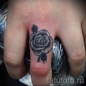 Фото тату: маленькая роза в технике blackwork на пальце руки. Детализированный рисунок татуировки, выполненный в минималистичном стиле.