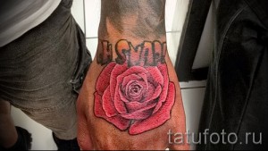 Фото тату: красная татуировка розы с надписью LOVE на руке, выполненная в традиционном стиле. Идеальный эскиз для тех, кто хочет выразить свою любовь.