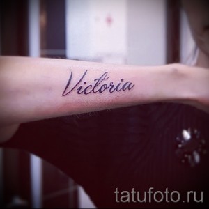 Фото тату с надписью 'Victoria' на запястье. Черные чернила, каллиграфический шрифт, минималистичный дизайн. Идеально для поклонниц именных татуировок.