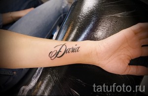 Фото минималистичной татуировки с именем "Daria", выполненным тонким черным шрифтом на запястье.