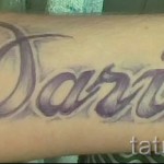 Фото татуировки с именем "Дарина", выполненным каллиграфическим шрифтом в фиолетовых и серых тонах на предплечье.