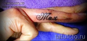 Фото тату с надписью 'Max' на пальце. Черно-белая татуировка, выполненная каллиграфическим шрифтом, небольшого размера.
