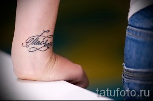 Фото тату надписи 'Alisa' на женском запястье, выполненной в каллиграфическом стиле с использованием тонких линий и черных чернил.