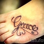 Фото тату имени 'Grace' с изображением пера на стопе. Черно-серый рисунок татуировки, нежный эскиз тату для девушки.