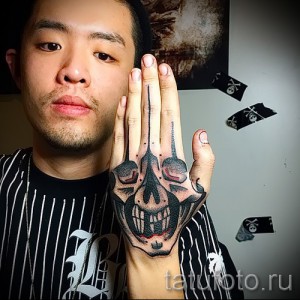 Фото тату черепа на руке, с яркими красными акцентами и детализированной проработкой. Оригинальный рисунок татуировки.