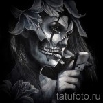 Мрачный эскиз татуировки с изображением девушки, наполовину превратившейся в череп, окруженной цветами. Детализированный рисунок в стиле чикано.