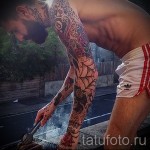 Фото тату на руке: полный рукав татуировок с различными рисунками, включая розы, черепа и геометрические узоры. Детализированный и красочный рисунок татуировки.