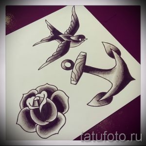 Эскиз татуировки в стиле олд скул с изображением летящей ласточки, морского якоря и распускающейся розы, выполненный в черных тонах.
