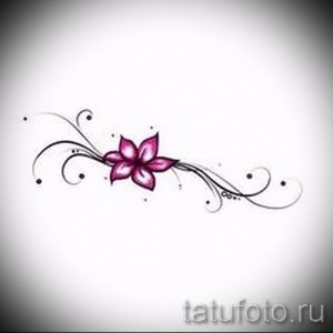Фотография эскиза татуировки с изображением небольшого розового цветка, окруженного тонкими черными линиями и точками.