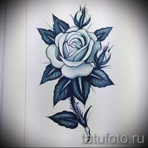 Фото тату с изображением раскрывающейся розы и двух бутонов. Рисунок выполнен в черно-серых тонах с плавными переходами и детализированными листьями.