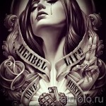 Черно-белое фото тату на плече с изображением плачущей девушки, держащей в руках пистолет и розу. Детализированный рисунок в стиле чикано с надписями.