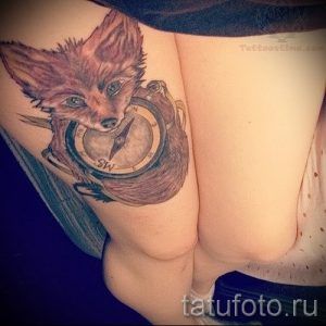 Фото татуировки лисы с компасом на плече. Рисунок выполнен в коричневых и серых тонах, с добавлением элементов морской тематики.
