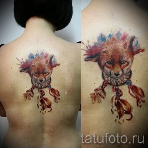 Фото акварельной татуировки лисы с ловцом снов на спине, выполненной в ярких и насыщенных цветах.