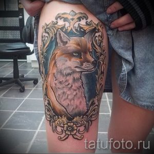 Фото тату лисы в старинной рамке на бедре. Рисунок выполнен в реалистичном стиле с использованием теплых коричневых и золотых оттенков.