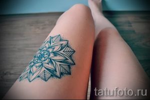 Фотография черно-белой татуировки мандалы на бедре девушки. Детализированный рисунок с тонкими линиями и точками.
