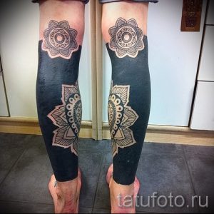 Фотография двух ног с татуировками мандал, выполненными в черном цвете. Татуировки расположены на голенях и коленях, создавая эффект симметрии.