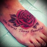 Фото тату: красная роза с надписью "The Worst Things Beautiful" на стопе. Элегантный и личный рисунок татуировки.