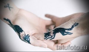 Фото минималистичных татуировок лис, выполненных черными линиями на ладонях двух людей, держащихся за руки.