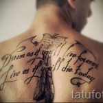 Фото тату на спине с изображением пера и надписью 'Dream as if you'll live forever. Live as if you'll die today'. Черно-белый рисунок.