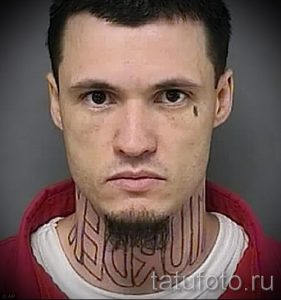 Фото тату на лице и шее мужчины: надписи и узоры, выполненные черными чернилами. Рисунок татуировки охватывает щеки, виски и шею.