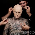 Фото тату: мужчина с полным тату в стиле биомеханика, с изображением вируса и работающими мастерами.