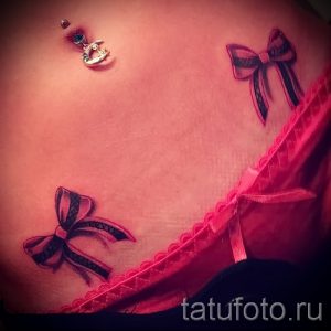 Фото тату: два черных бантика на животе. Эффектный и романтичный рисунок татуировки, выполненный в реалистичном стиле, подчеркивает женственность и красоту.