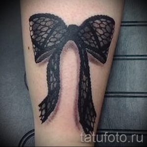 Фото тату кружевного банта на предплечье. Черно-белый рисунок татуировки в стиле реализм.