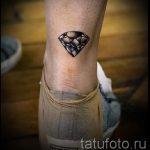 Фото тату: небольшой черный бриллиант, выполненный в графичном стиле, на лодыжке. Простой и элегантный рисунок татуировки.