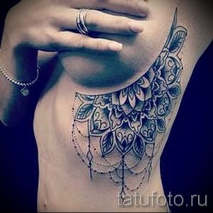 Фото тату мандалы на боку, выполненной в черном цвете. Изящные линии и узоры создают женственный и привлекательный образ.