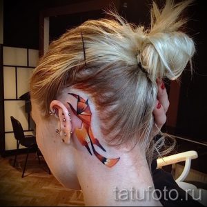 Фото акварельной татуировки лисы на затылке. Размытые линии, яркие цвета, эффект текущей краски.