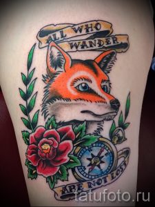 Фото тату лисы на руке в стиле олд скул. Компас, роза, надпись 'All who wander are not lost', яркие цвета.