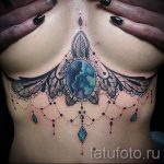 Фото тату мандалы на груди. Цветной рисунок с использованием ярких оттенков и драгоценных камней. Оригинальный эскиз тату для девушек.