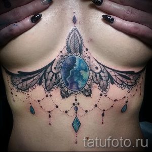 Фото тату мандалы на груди. Цветной рисунок с использованием ярких оттенков и драгоценных камней. Оригинальный эскиз тату для девушек.