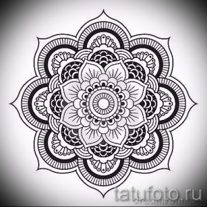 Фото тату: черно-белая мандала с круговыми узорами и детальной проработкой лепестков, выполненная в графическом стиле.