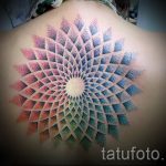 Фото тату: большая мандала, выполненная в технике pointillism, расположена на спине. Рисунок состоит из множества разноцветных точек.