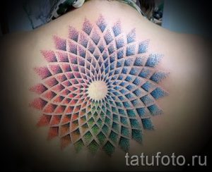 Фото тату: большая мандала, выполненная в технике pointillism, расположена на спине. Рисунок состоит из множества разноцветных точек.