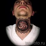 Фото татуировки: черная мандала с символом Ом на шее мужчины, вид спереди, детализированный узор, религиозный символ.